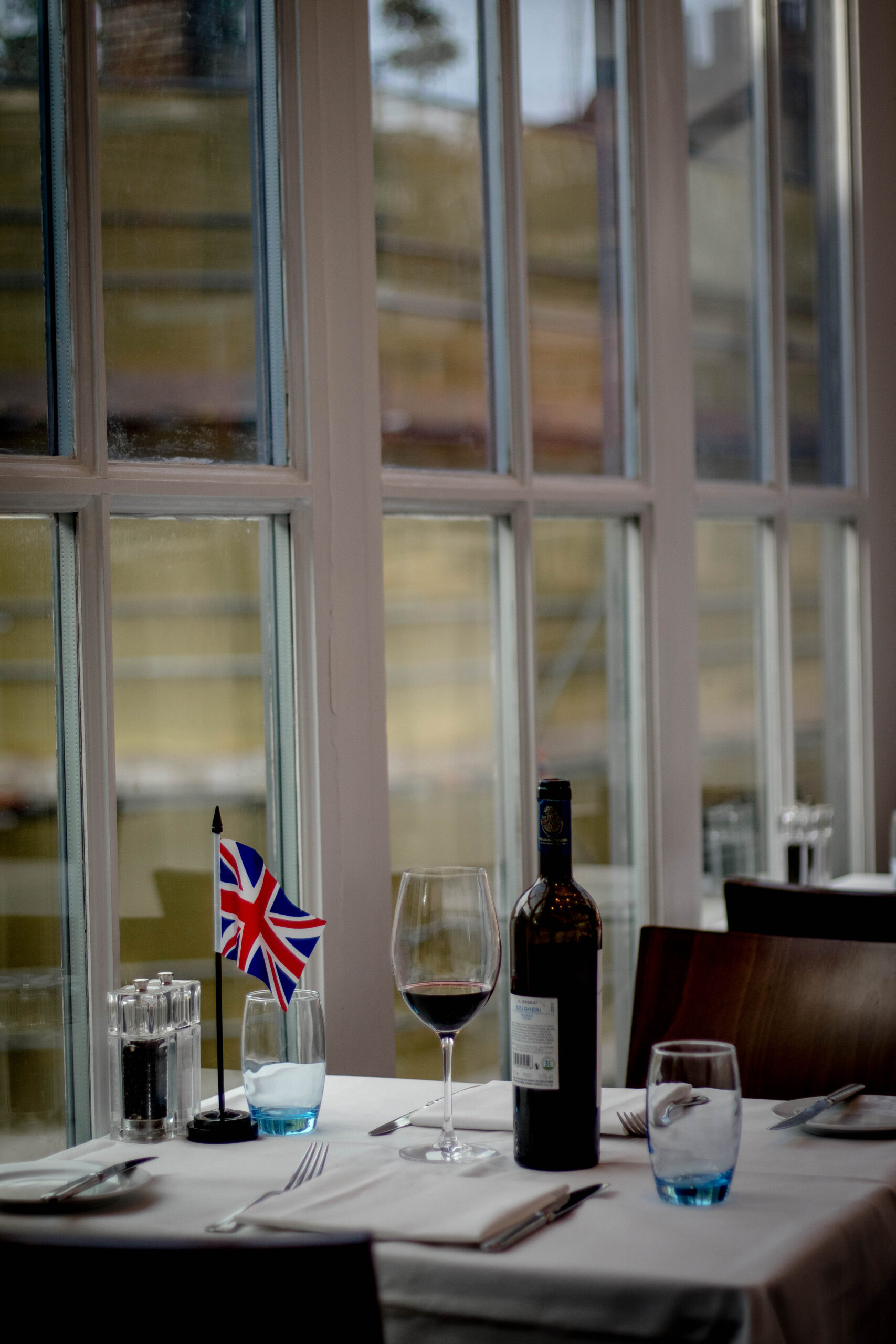 Nicely set restaurant table with a glass and bottle of wine on it.